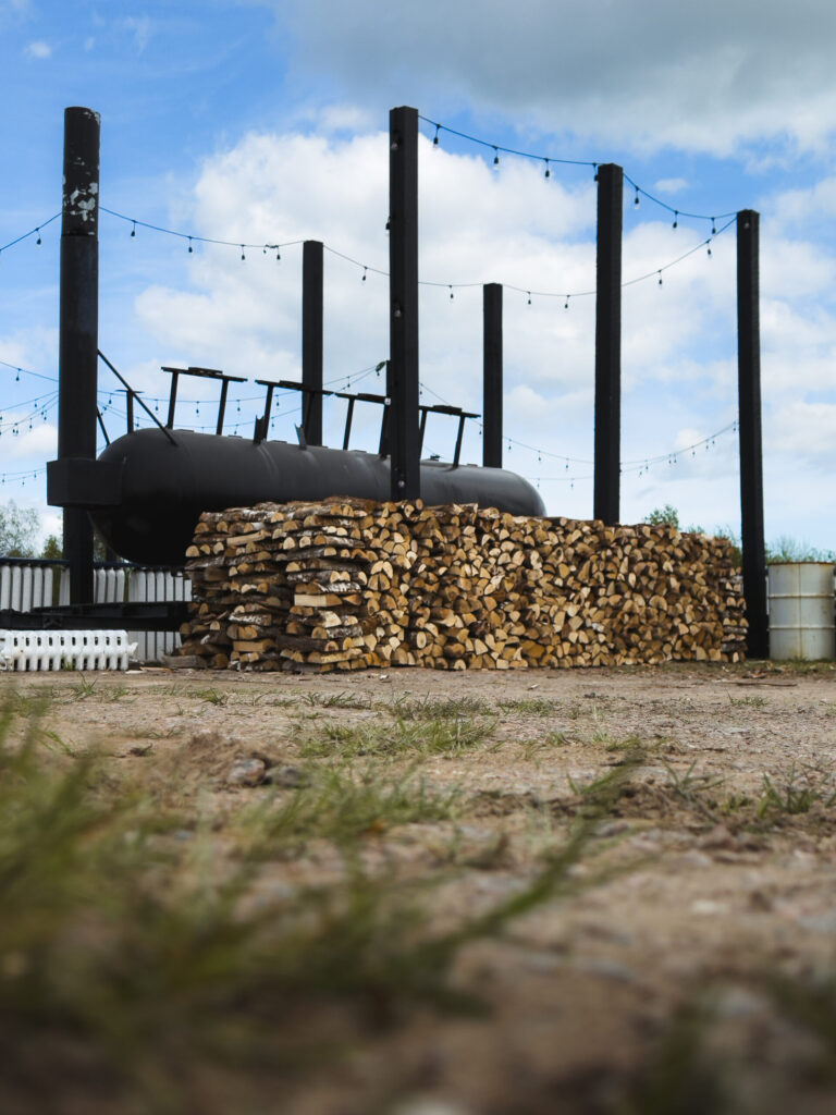 Three layers of stacked and split logs wait their destiny behind the thousand-gallon smoker at Shediac's Neptune Drive-In Theatre