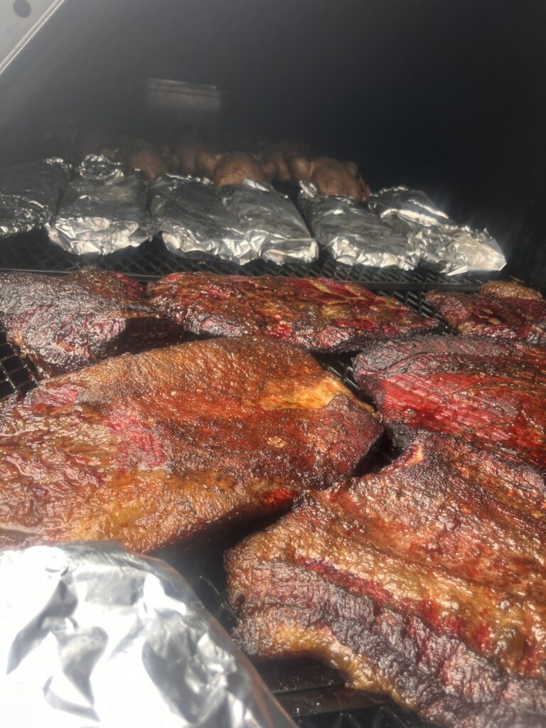 Briskets and wrapped ribs and smoked chickens inside a smoker.